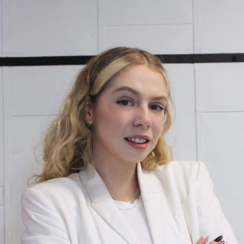 Nicole Gartner headshot image with white jacket and arms folded.